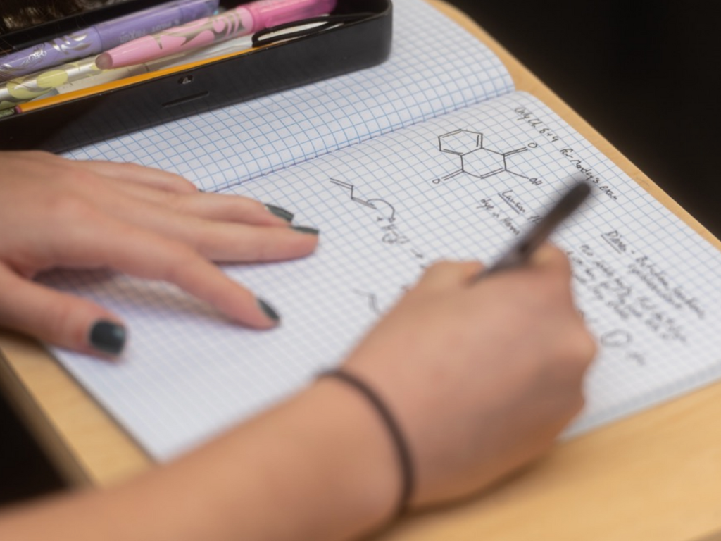 Student writing in a lab notebook