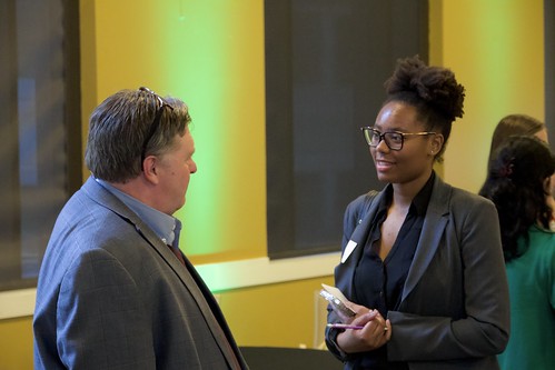 Student in blazer discussing career opportunities with a recruiter in a professional setting.