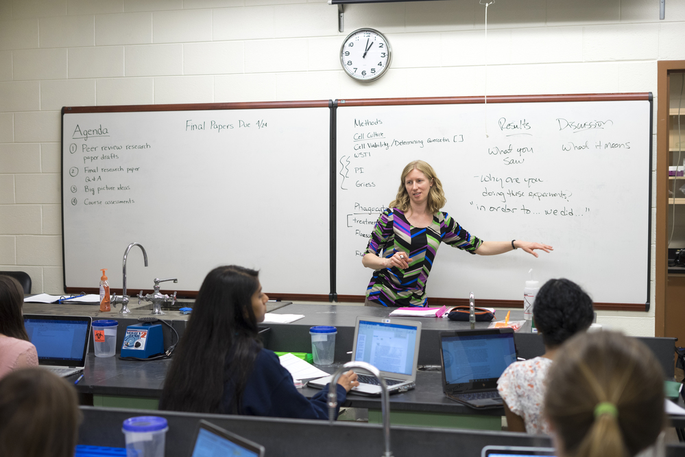 Instructor in front of a class, pointing to a white board