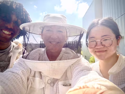 Three people, including a woman in a bee-keeping hat.
