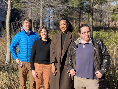 Group of people standing outside in the sun smiling.