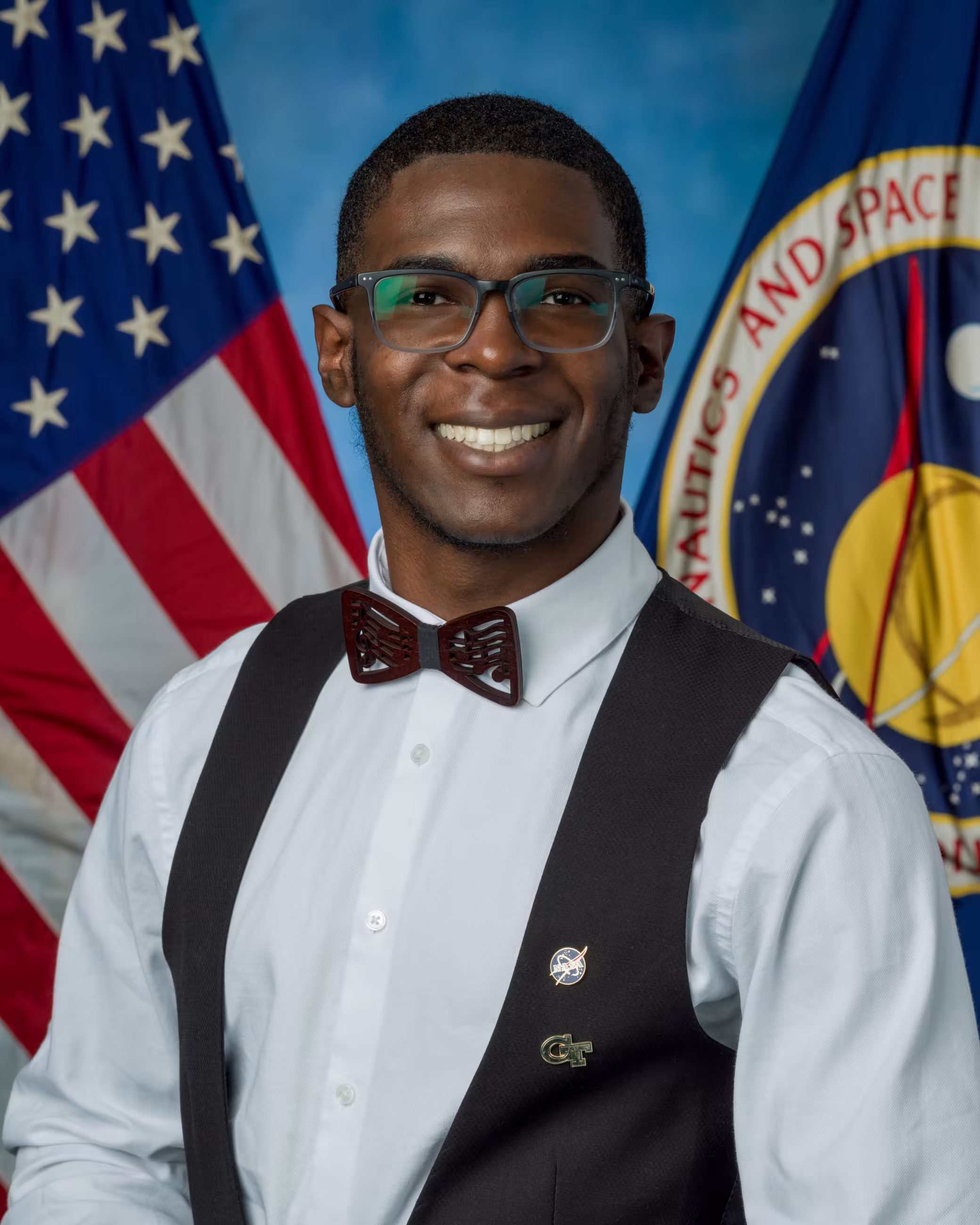 Photo of student J'Avani Stinson in front of an American flag and NASA flag